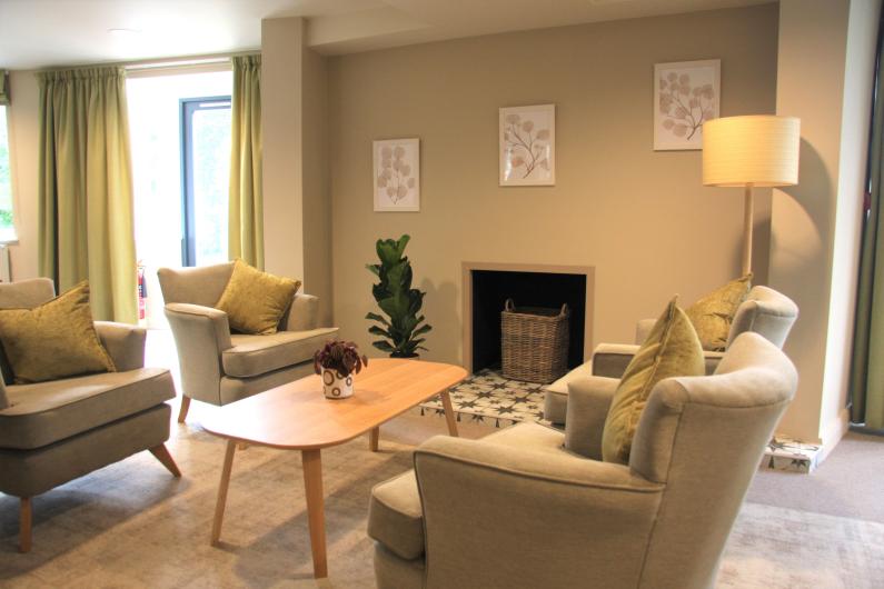 A large living room with four cream arm chairs placed around a wooden coffee table.