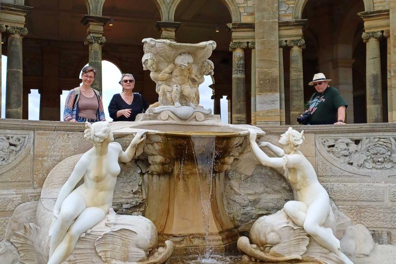 A water fountain with sculptures either side and archways behind