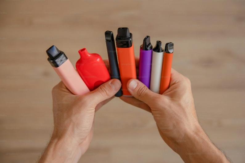 Hand holding a number of coloured disposable vapes