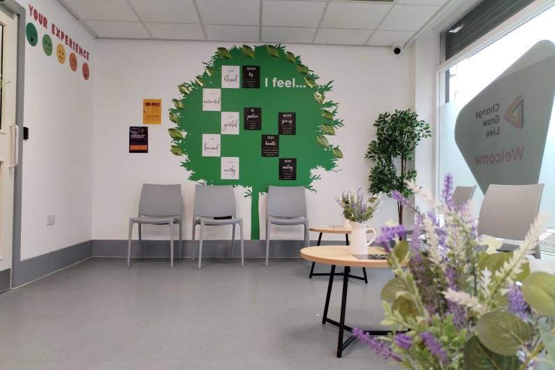 A waiting room area with a green tree painted on the wall