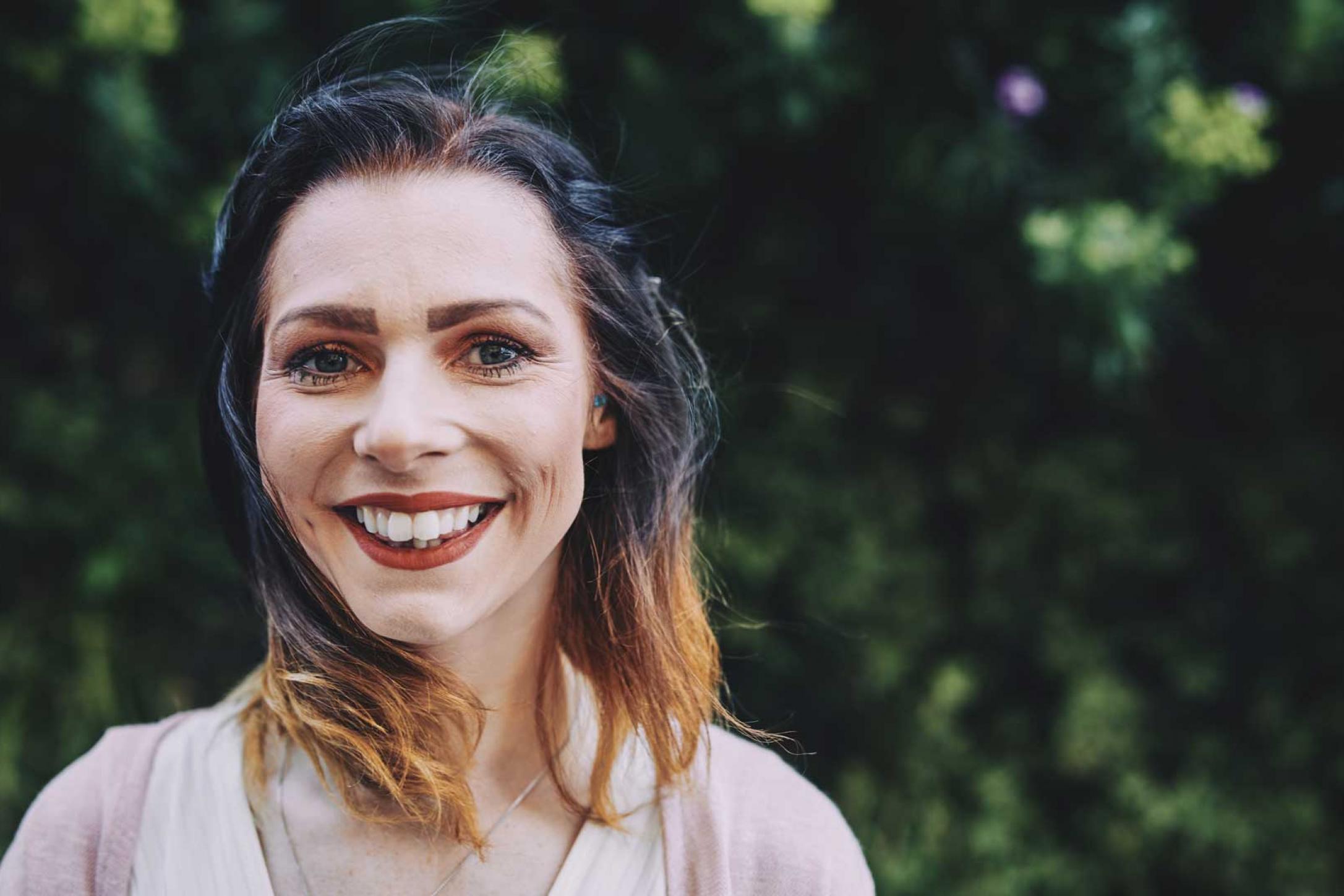 woman smiling standing in front of a tree